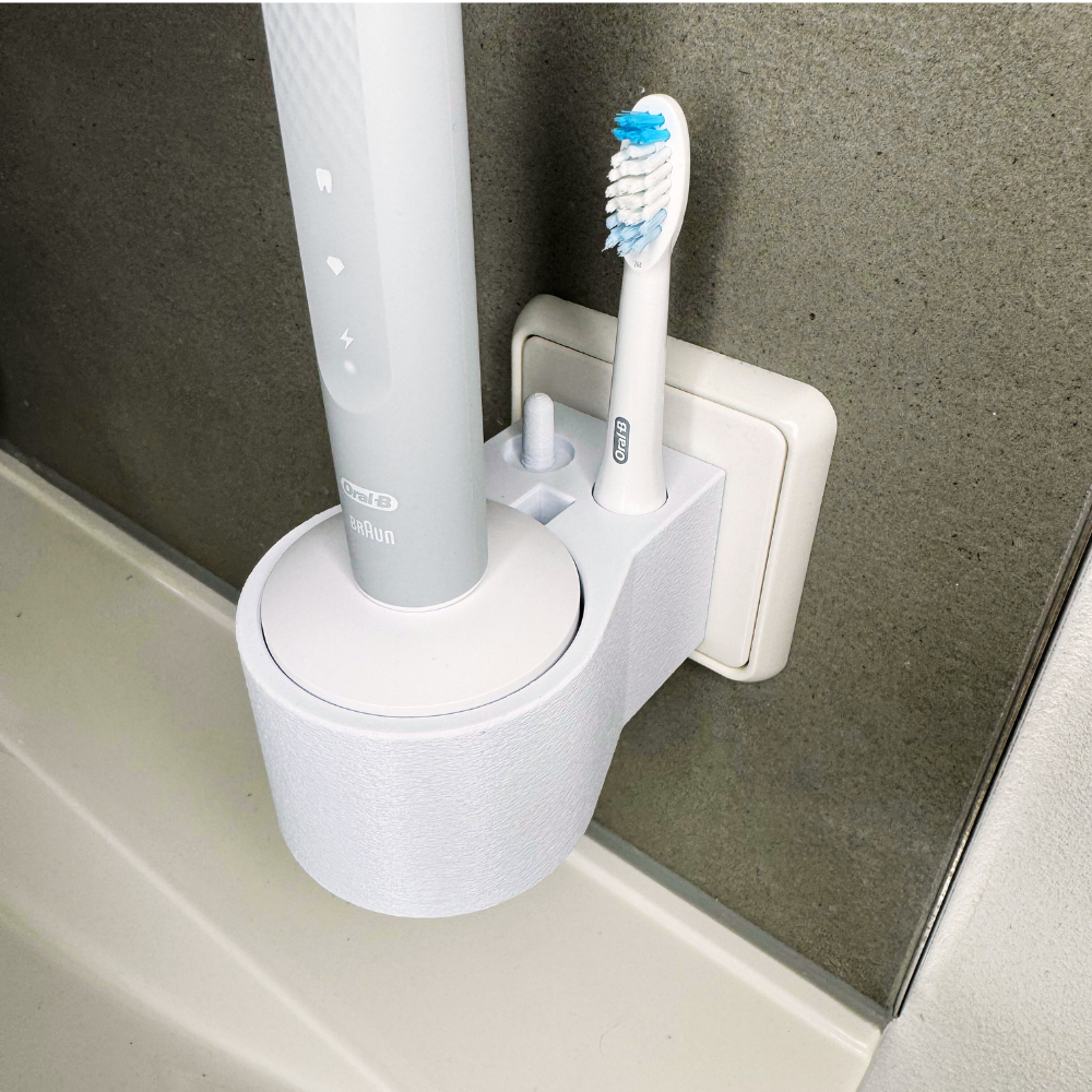Oral B Pulsonic Slim Clean Zahnbürstenhalterung die direkt in eine Steckdose eingesteckt ist.Die Halterung ist so gestaltet, dass keine Kabel sichtbar sind. Praktische Lösung, um die Zahnbürste aufzubewahren und gleichzeitig den Raum ordentlich zu halten.