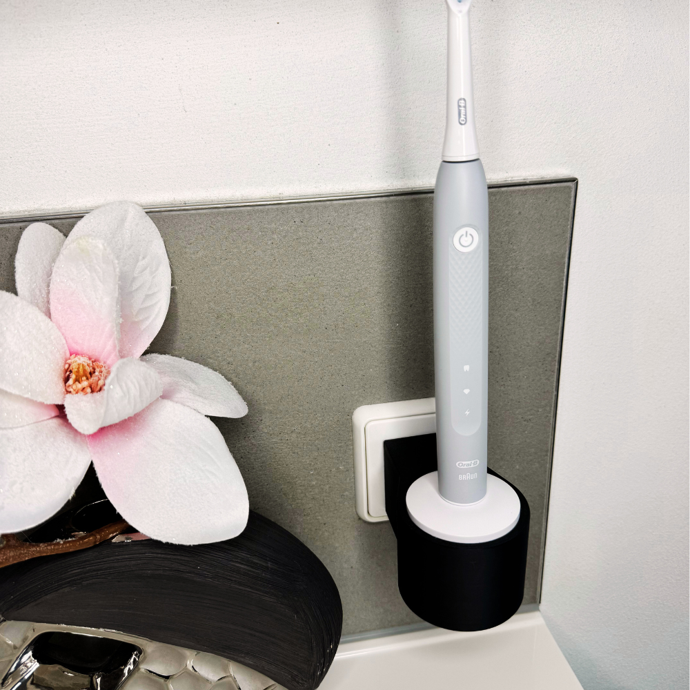 Oral B Pulsonic Slim Clean Zahnbürstenhalterung die direkt in eine Steckdose eingesteckt ist.Die Halterung ist so gestaltet, dass keine Kabel sichtbar sind. Praktische Lösung, um die Zahnbürste aufzubewahren und gleichzeitig den Raum ordentlich zu halten.