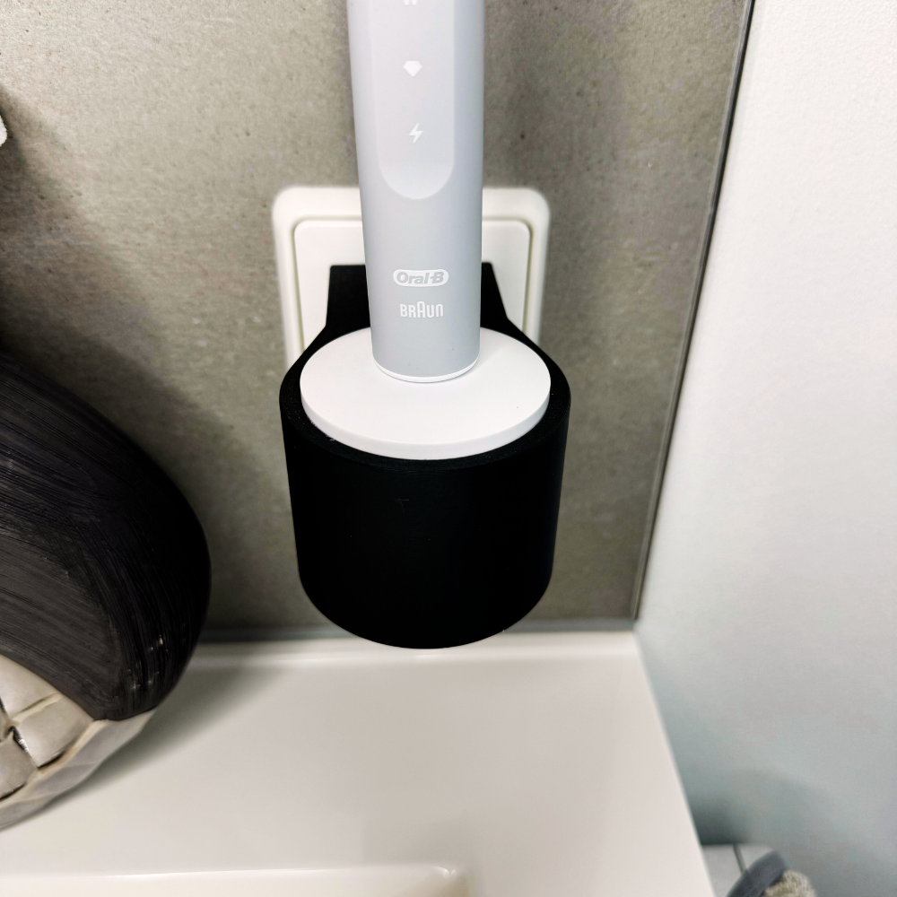 Oral B Pulsonic Slim Clean Zahnbürstenhalterung die direkt in eine Steckdose eingesteckt ist.Die Halterung ist so gestaltet, dass keine Kabel sichtbar sind. Praktische Lösung, um die Zahnbürste aufzubewahren und gleichzeitig den Raum ordentlich zu halten.