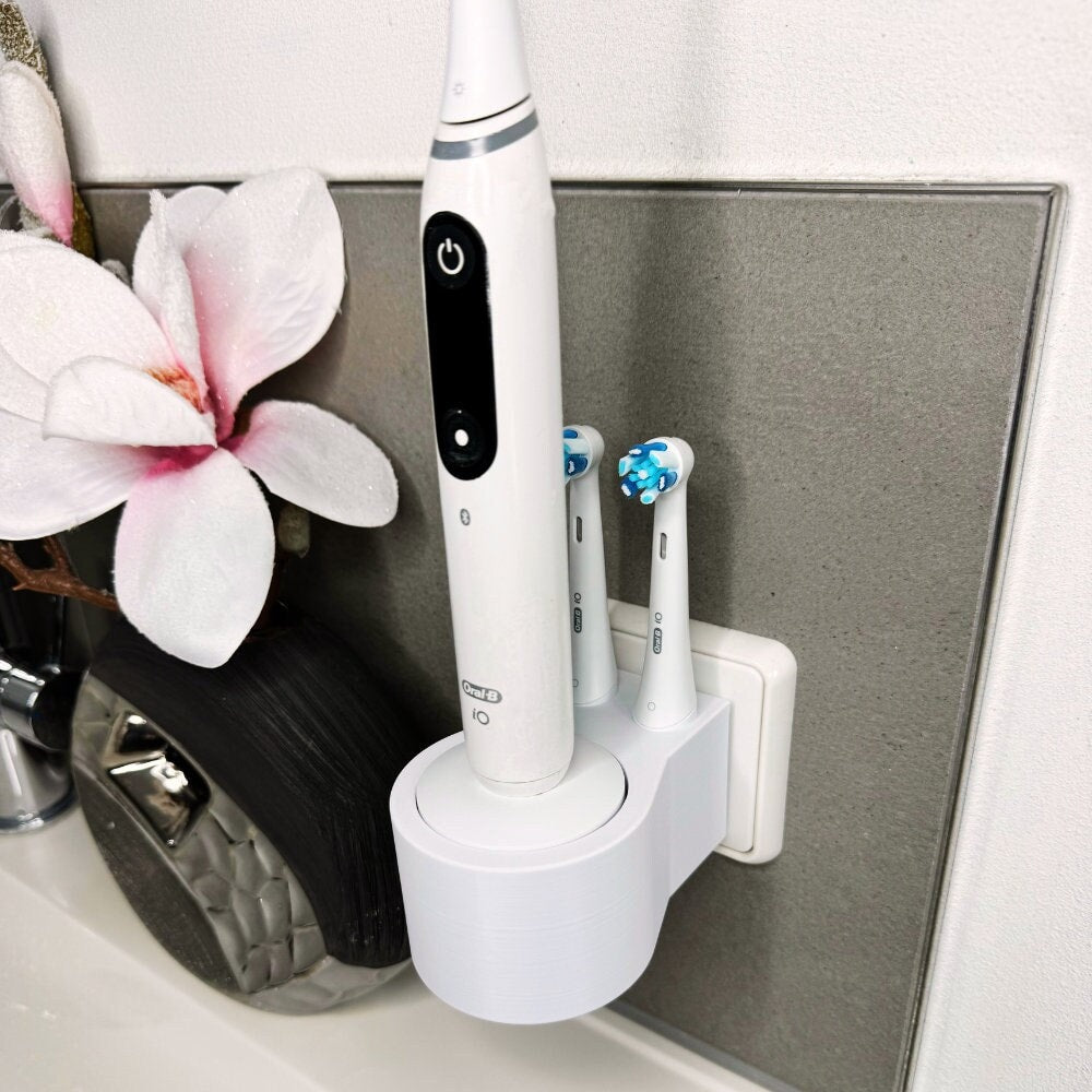 Oral B IO 7,8,9 Zahnbürstenhalterung die direkt in eine Steckdose eingesteckt ist.Die Halterung ist so gestaltet, dass keine Kabel sichtbar sind. Praktische Lösung, um die Zahnbürste aufzubewahren und gleichzeitig den Raum ordentlich zu halten.