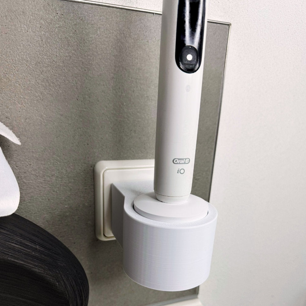 Oral B IO 7,8,9 Zahnbürstenhalterung die direkt in eine Steckdose eingesteckt ist.Die Halterung ist so gestaltet, dass keine Kabel sichtbar sind. Praktische Lösung, um die Zahnbürste aufzubewahren und gleichzeitig den Raum ordentlich zu halten.