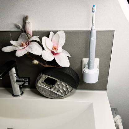 Oral B Pulsonic Slim Clean  Zahnbürstenhalterung die direkt in eine Steckdose eingesteckt ist.Die Halterung ist so gestaltet, dass keine Kabel sichtbar sind. Praktische Lösung, um die Zahnbürste aufzubewahren und gleichzeitig den Raum ordentlich zu halten.